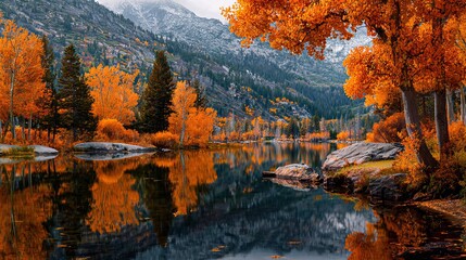 Obraz premium Stunning autumn landscape reflecting on a serene lake surrounded by vibrant orange trees and majestic mountains with a touch of snow