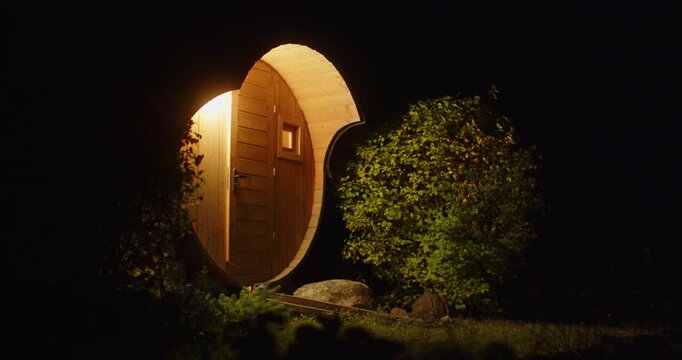 A round wooden building in the dark with a burning lantern