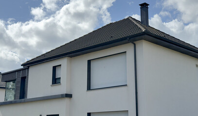 Modern white house with dark roof and closed shutters