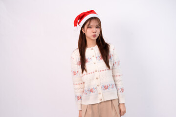 smiling pretty young woman wearing santa hat and festive cardigan for christmas in white studio...
