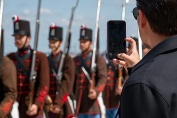 Person taking mobile photo of soldiers in historic uniform