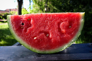 Close-up of a fresh, juicy slice of watermelon with visible seeds, vibrant red flesh, and a green rind, placed on a rustic wooden surface, perfect for a refreshing summer snack.