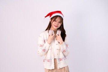young beautiful woman wearing santa hat and headphones smiling joyfully in white studio background
