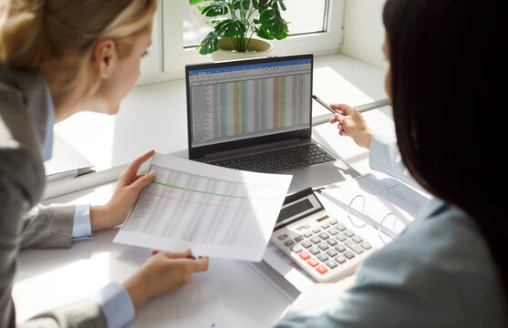 Two concentrated serious business people working in office sitting at the desk with laptop on workplace looking at computer monitor screen analyzing company finances. Accountant job concept. - Powered by Adobe