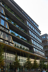 Obraz premium A large, modern building with numerous windows is beautifully surrounded by lush trees in a vibrant urban environment