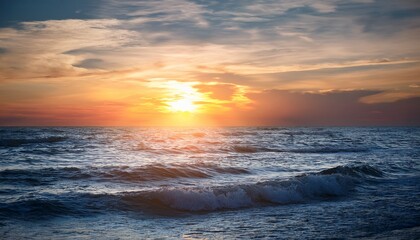 Fototapeta premium the sun slowly disappears behind the ocean horizon casting an ethereal glow across the waves and sky