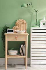 Wooden side table with stylish decor near green wall indoors