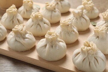 Uncooked khinkalis (dumplings) on wooden table, closeup