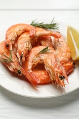 Tasty grilled shrimps served with rosemary and lemon on white wooden table, closeup. Delicious seafood dish