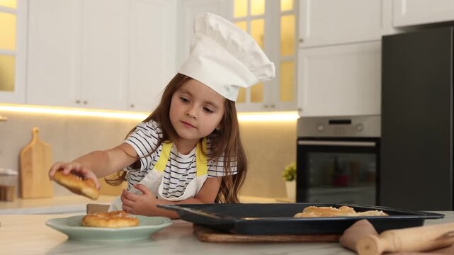 Choice of profession. Little girl with pastries pretending to be chef in kitchen