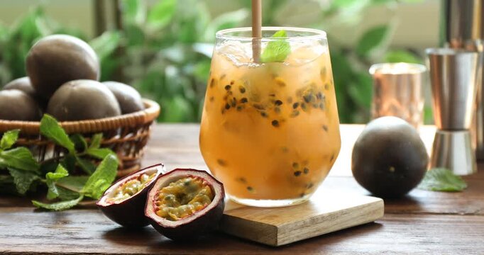 Stirring tasty passion fruit drink in glass on wooden table, closeup