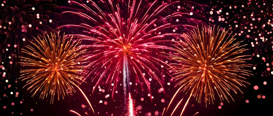 Colorful fireworks exploding in red sky with sparkling golden glitter foreground, festive New Year celebration background.