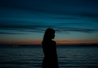 Silhouette of a woman looking at the sea during a colorful sunset