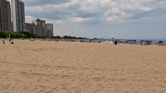 Tourists and locals cool off at the beach on Lake Michigan in Chicago, Illinois. Summer scene on a hot July day in the city. Located at the Ohio Street Beach. - Powered by Adobe