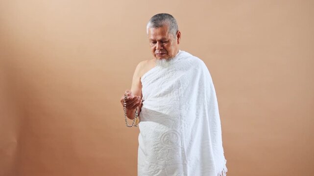 Devout Muslim Elderly in ihram holding prayer beads conveying peace and reflection
