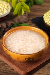 Rice porridge in ceramic bowl on wooden table with grains and natural ingredients