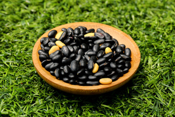 Black Beans and Sesame Seeds in Wooden Bowl on Green Grass - Healthy Organic Legumes and Grains