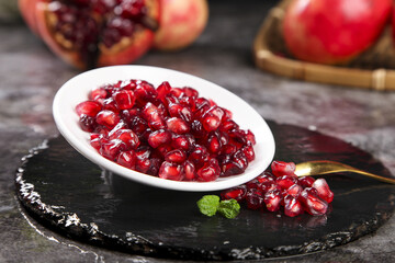 Fresh Pomegranate Seeds in White Bowl on Black Slate - Ruby Red Arils Superfruit Food Photography