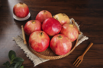 Fresh Organic Pomegranates in Rustic Wicker Basket on Dark Wood Table