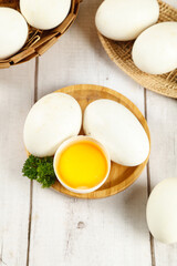 Fresh farm eggs in wicker tray with raw yolk on rustic wooden background