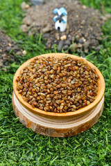 Buckwheat Groats in Wooden Bowl on Green Grass - Healthy Whole Grain Cereal for Organic Diet