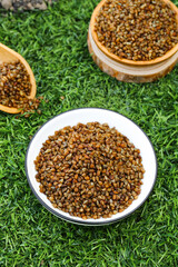 Organic buckwheat grains in wooden bowls on grass - healthy whole grain cereal and natural superfood ingredients