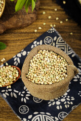 Buckwheat grains in burlap sack on wooden table - healthy organic cereal food ingredient