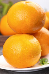 Fresh Ripe Oranges on White Plate with Green Leaves - Healthy Citrus Fruit Display