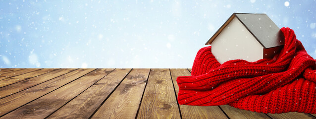 A house model rests on a table under a red blanket
