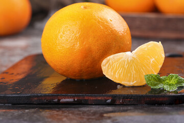 Freshly picked orange with segments and mint on wooden board - healthy citrus fruit display