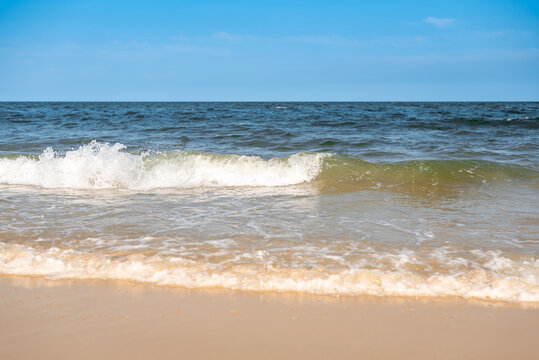 Small waves carsh on a warm sandy beach.