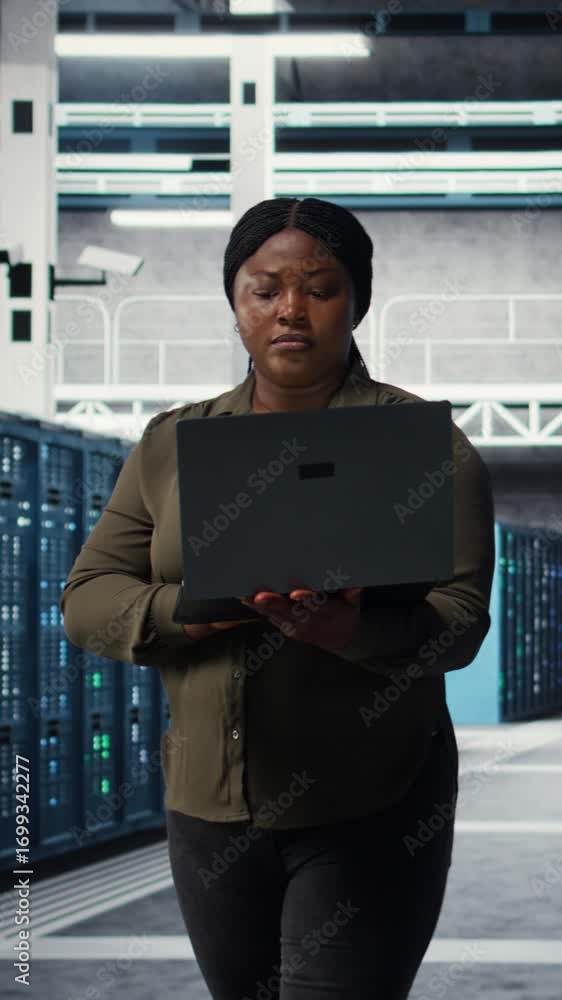 Aufkleber vertical video smiling engineer walking in data center with laptop, checking hardware for system sta