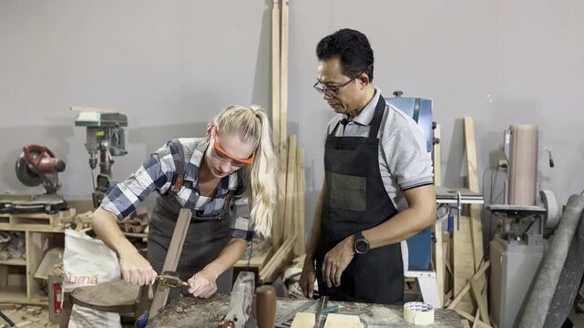 Master Craftsmen at Work: Two individuals, a woman and a man, are engrossed in woodworking, surrounded by tools and materials in a workshop setting.