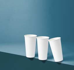 Three white 22 oz paper cups placed on the edge of a blue background.