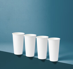 Four white 22 oz paper cups sit on the edge of a blue background.
