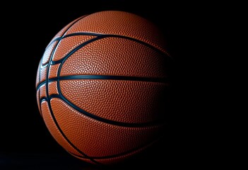 Obraz premium Close-up of basketball on pure black background, dramatic lighting, texture, equipment