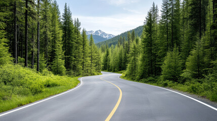 Fototapeta premium Winding road through lush green forest with mountains in background, creating serene atmosphere
