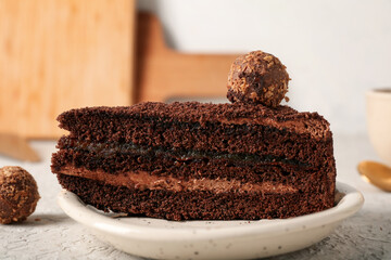 Plate with piece of tasty chocolate cake and candies on white table, closeup