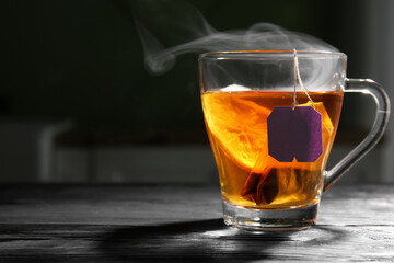 Cup of tasty black tea with lemon on black wooden table, closeup