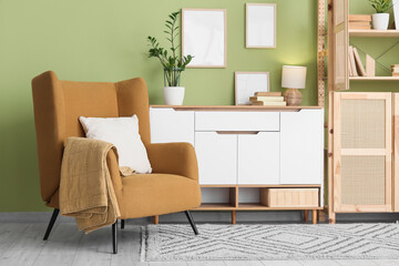 Interior of living room with comfortable armchair, chest of drawers and book shelf, closeup