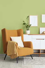Interior of living room with comfortable armchair and chest of drawers, closeup