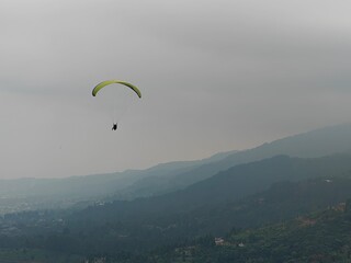 Paraglider Flying Over Mountain Landscape on a Cloudy Day