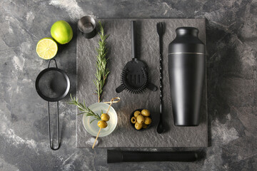 Modern bartender kit and cocktail ingredients on grey grunge background
