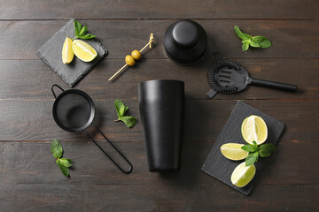 Composition with bartender utensils and cocktail ingredients on black wooden background
