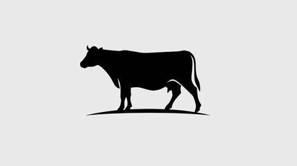 Silhouette of a cow standing on a simple grassy hill.