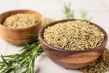 Bowls with dried rosemary on white tile background, closeup