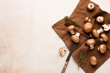 Napkin, knife and raw champignon mushrooms on white grunge background, closeup