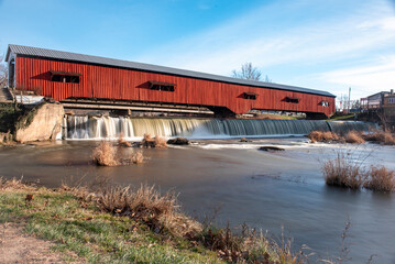 A historic covered bridge over a water fall
