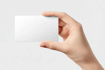 Obraz premium A hand holding a blank white business card on a plain white background, ideal for mockups or customizable design presentations