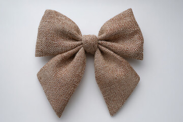 A large decorative bow made of textured burlap fabric, tied symmetrically with wide loops and tails, displayed against a plain white background